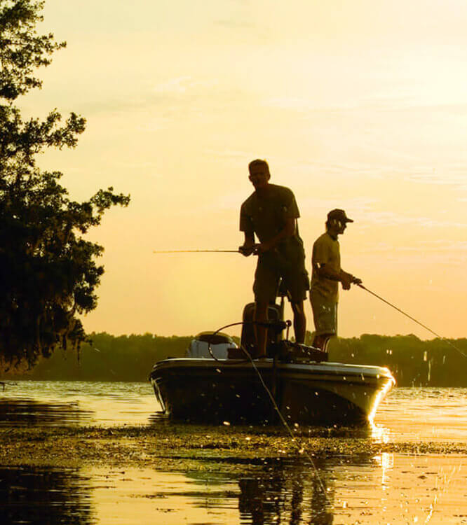 Zwei Angler auf einem Boot im Gegenlicht der Abendsonne.