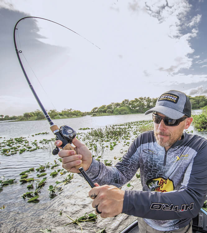 Angler drillt einen Fisch mit stark gebogener Rute vom Boot aus.
