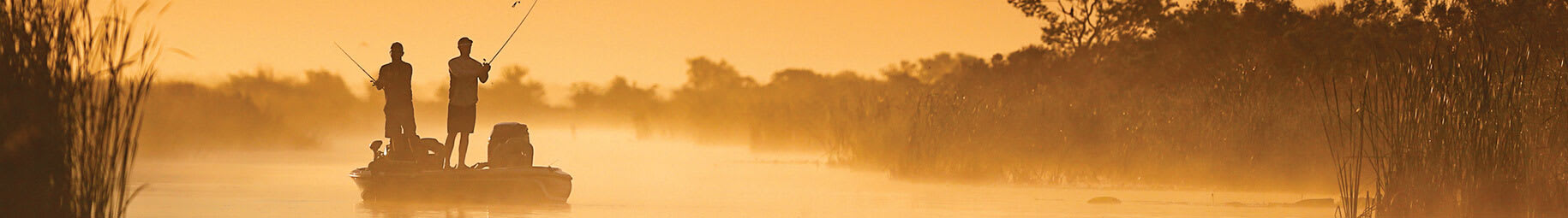 Zwei Angler auf einem Boot im Morgennebel bei goldenem Sonnenaufgang.