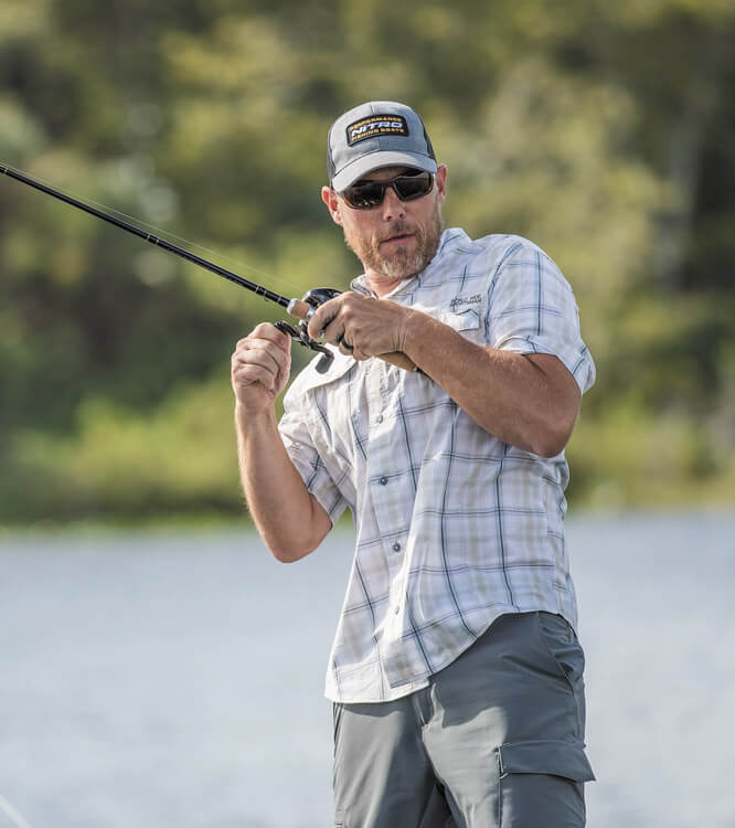 Angler wirft mit einer Rute-Rollen-Kombination am Ufer aus.