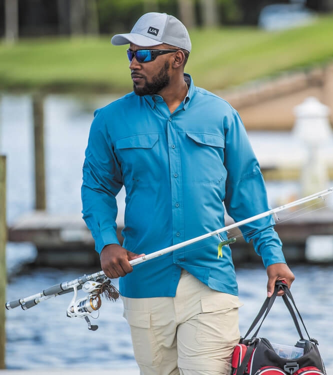 Angler in blauem Langarm-Angelshirt mit Rute und Tackletasche.