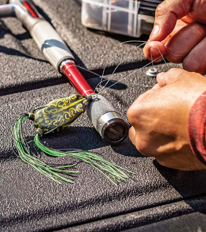 Angler montiert einen Jig an der Hauptschnur auf dem Bootsdeck.
